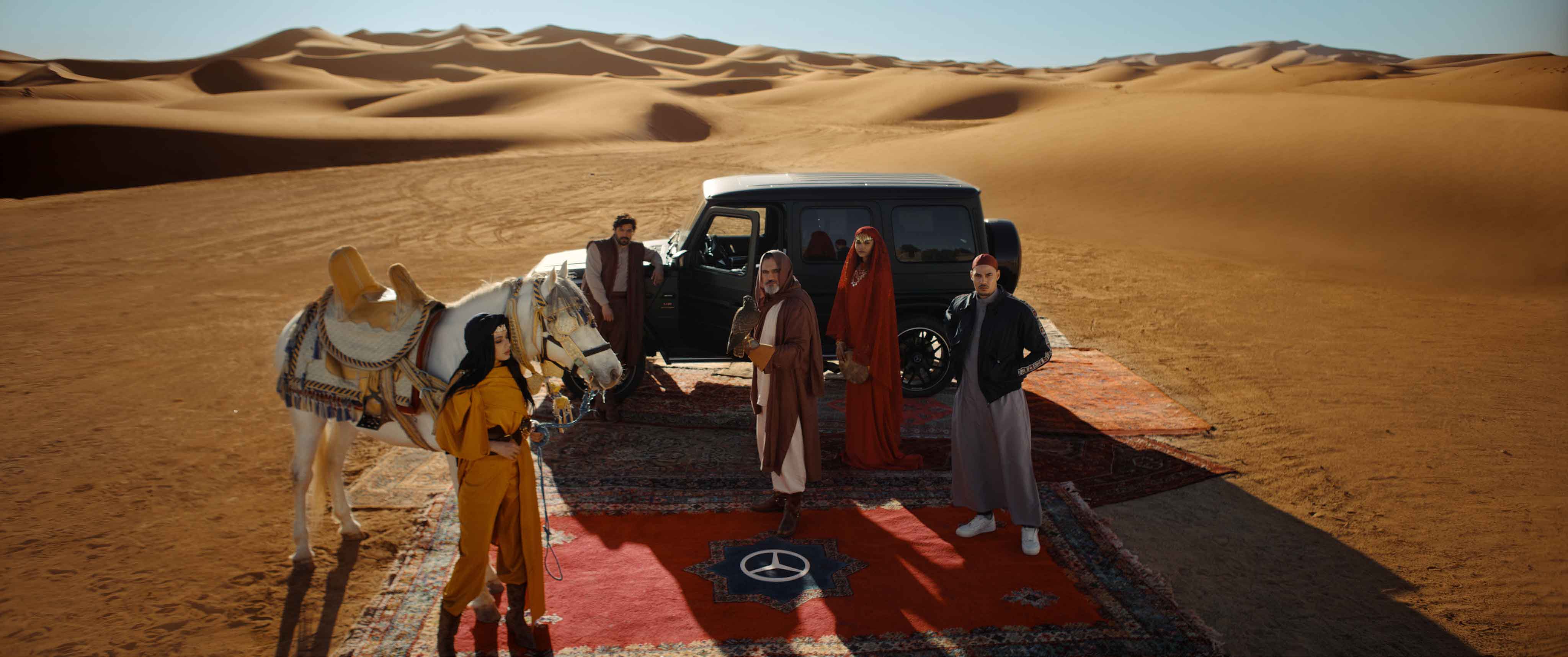 Mercedes-Benz MENA commercial scene in the Moroccan desert, featuring a black G-Class, Arabian horse, falcon, and models in traditional and modern attire, directed by Farid Malki.